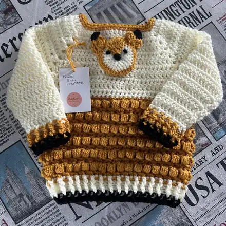 Cream baby jumper with a crocheted fox face on the front