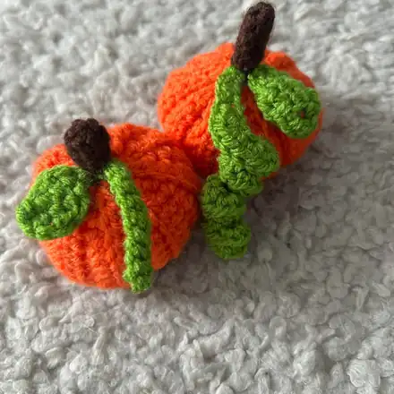 Two orange crochet pumpkins with green leaves