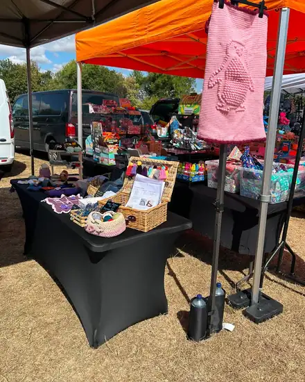An outdoor market stall under an orange gazebo with crochet items on display