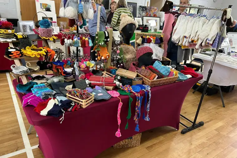 The Snug @ No 39 stall at an indoor Christmas fair, tables full of colourful crochet